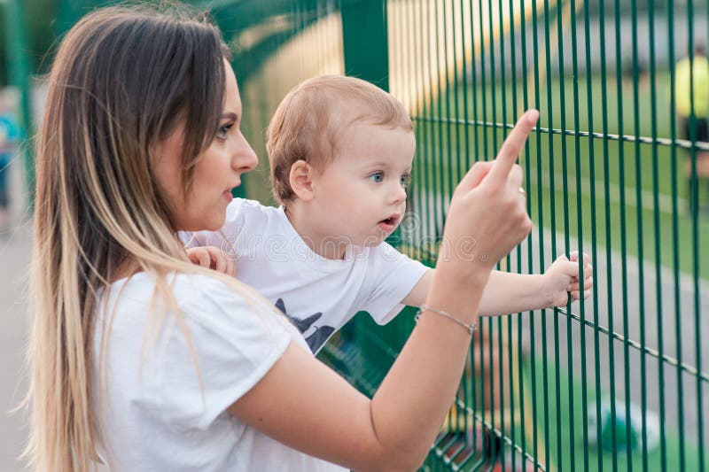 Glückliche Mutter hält netten lächelnden Sohn im Park stockbilder Glückliche Mutter hält netten lächelnden Sohn im Park stockbilder