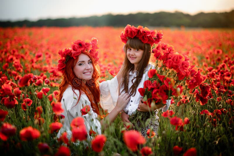 Glückliche Mutter und kleine Tochter, die auf dem blühenden Gebiet in den Kränzen von wilden Mohnblumenblumen sitzt stockfotos Glückliche Mutter und kleine Tochter, die auf dem blühenden Gebiet in den Kränzen von wilden Mohnblumenblumen sitzt stockfotos