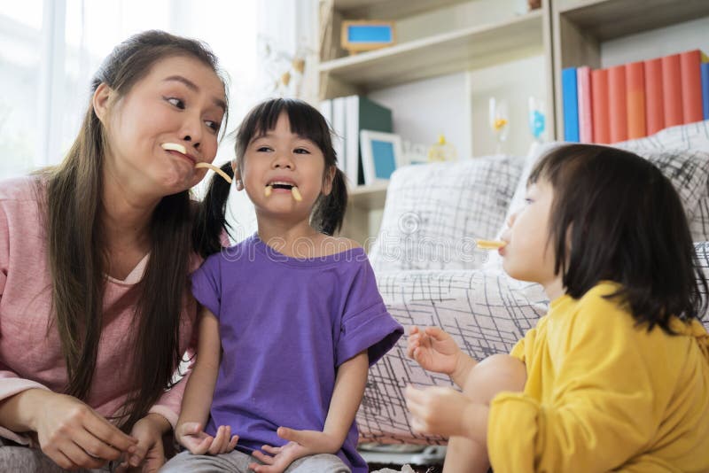 Glückliche Mutter und Tochter essen zu Hause Cracker lizenzfreies stockfoto