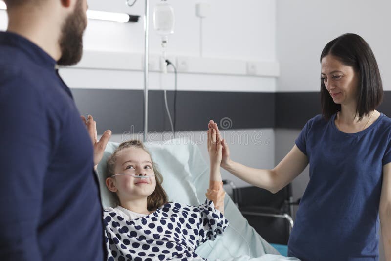 Glückliche Mutter und Vater gratulieren kranken kleinen Tochter zu einer erfolgreichen Behandlung lizenzfreies stockfoto