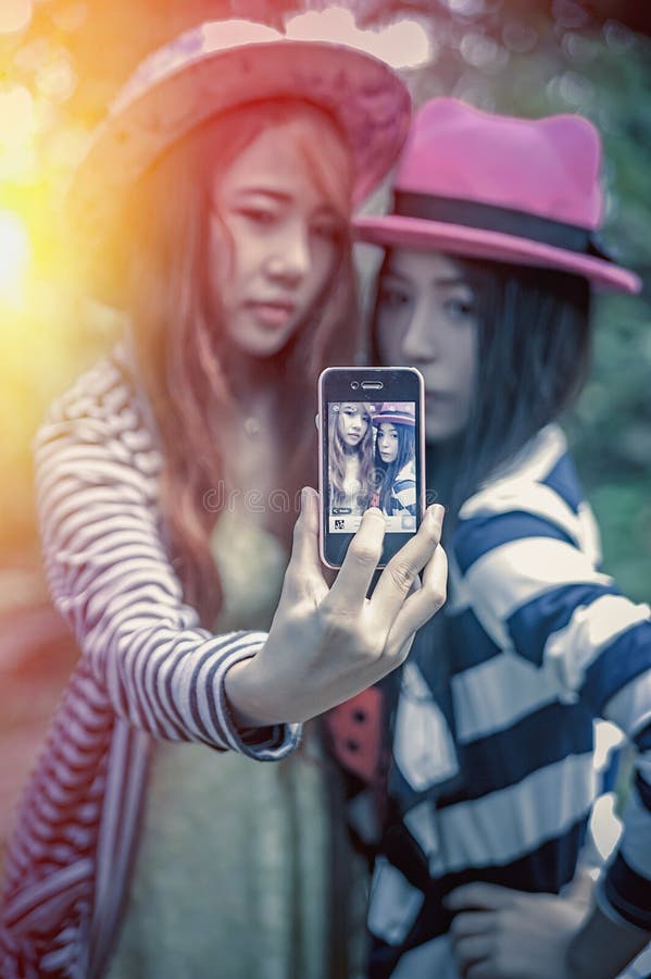 Glückliche Mädchen Asiens, die selfie am Park nehmen lizenzfreies stockfoto Glückliche Mädchen Asiens, die selfie am Park nehmen lizenzfreies stockfoto