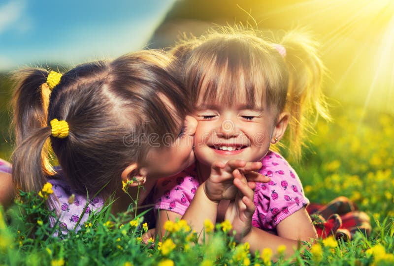 Glückliche Mädchenzwillingsschwestern, die im Sommer küssen und lachen lizenzfreie stockfotografie