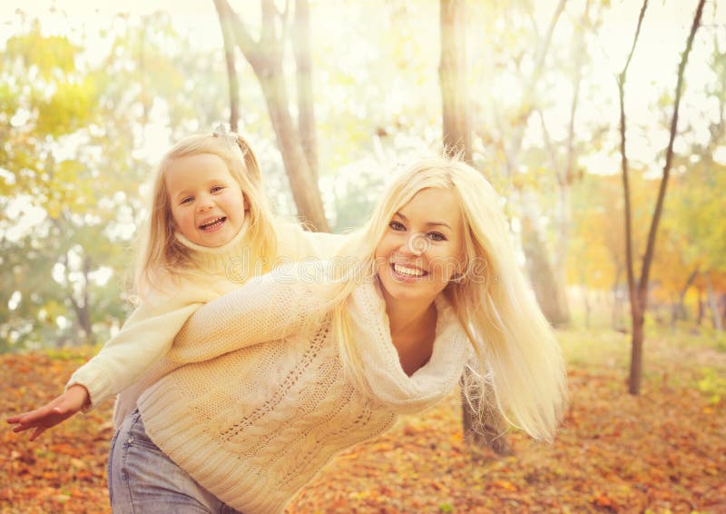 Glückliche nette Mutter, die lächelndes Baby und Spiel im sonnigen Herbstpark zusammenhält stockbild Glückliche nette Mutter, die lächelndes Baby und Spiel im sonnigen Herbstpark zusammenhält stockbild