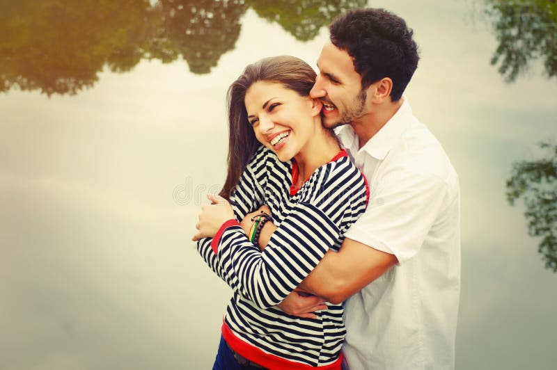 Glückliche romantische breite Lächelnpaare in der Liebe am See im Freien an lizenzfreie stockfotos Glückliche romantische breite Lächelnpaare in der Liebe am See im Freien an lizenzfreie stockfotos
