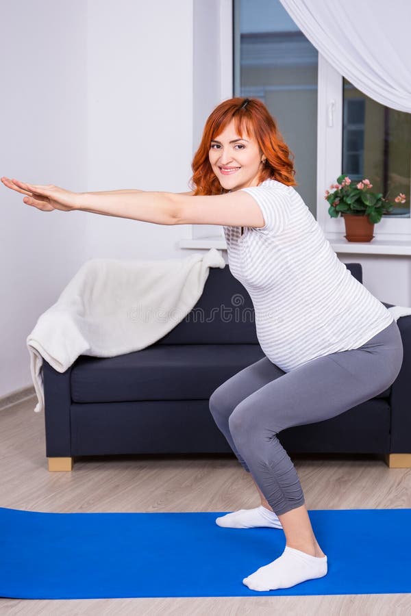 Glückliche schwangere Frau, die zu Hause hockt lizenzfreie stockfotos Glückliche schwangere Frau, die zu Hause hockt lizenzfreie stockfotos