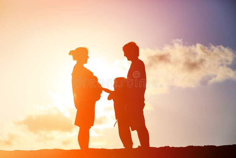 Glückliche schwangere Mutter und Vater mit Sohn bei Sonnenuntergang stockbild Glückliche schwangere Mutter und Vater mit Sohn bei Sonnenuntergang stockbild