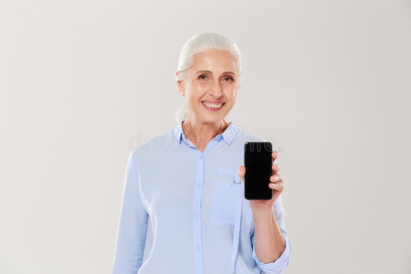 Glückliche schöne reife Frau, die Smartphone mit dem leeren schwarzen Schirm lokalisiert zeigt stockbild Glückliche schöne reife Frau, die Smartphone mit dem leeren schwarzen Schirm lokalisiert zeigt stockbild