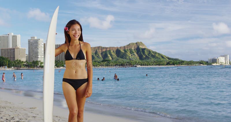 Glückliche Schönheitsstellung mit Surfbrett an waikiki Strand