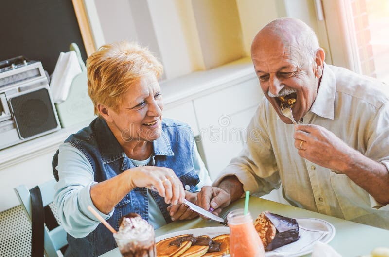 Glückliche Seniorpaare, die Pfannkuchen in einem Barrestaurant - reife Leute haben den Spaß zusammen zu Hause speist essen lizenzfreies stockfoto Glückliche Seniorpaare, die Pfannkuchen in einem Barrestaurant - reife Leute haben den Spaß zusammen zu Hause speist essen lizenzfreies stockfoto