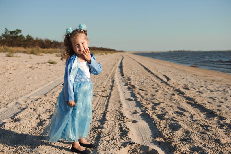 Glückliche Tochter auf dem Strand in einem blauen Kleid stockbild Glückliche Tochter auf dem Strand in einem blauen Kleid stockbild