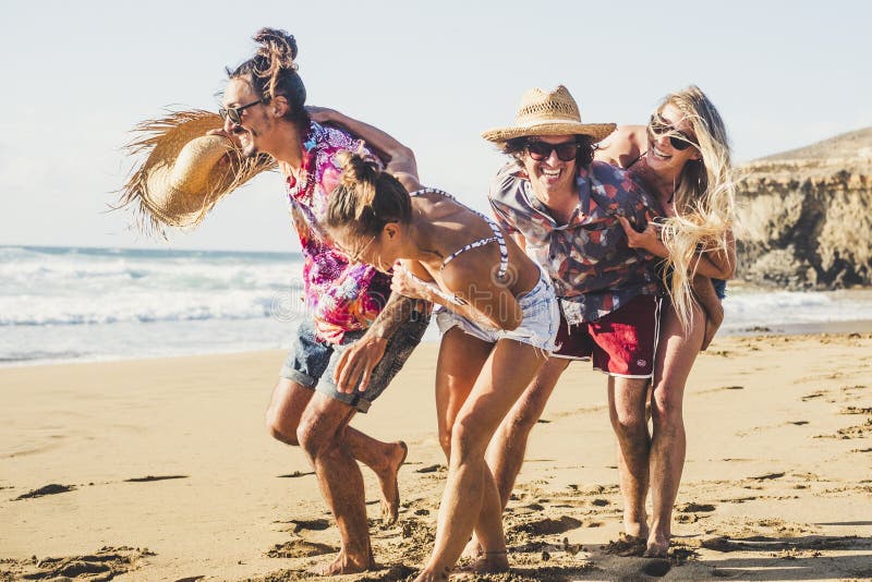 Glückliche und fröhliche Gruppe junger Hipster-Paare, die sich im Freien am Strand amüsieren und spielen und sich gemeinsam amüsi stockfotografie Glückliche und fröhliche Gruppe junger Hipster-Paare, die sich im Freien am Strand amüsieren und spielen und sich gemeinsam amüsi stockfotografie