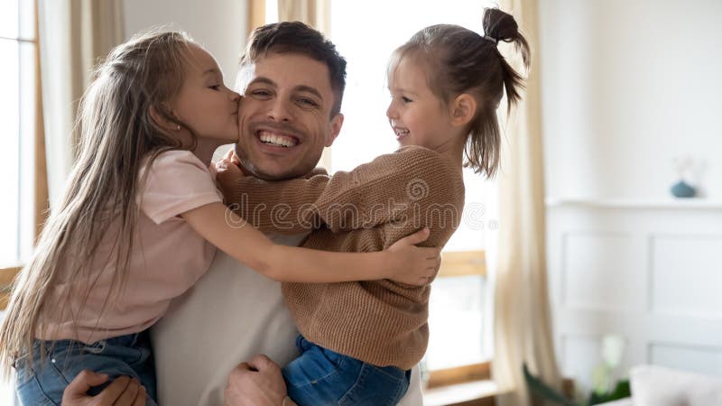 Glückliche Vaterholding, die zwei schöne Töchter umarmt lizenzfreie stockfotografie