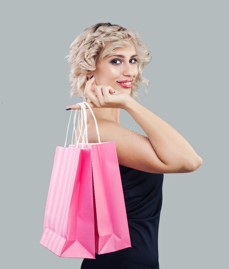 Glückliche vorbildliche Frau, die rosa Einkaufstasche hält stockbilder Glückliche vorbildliche Frau, die rosa Einkaufstasche hält stockbilder