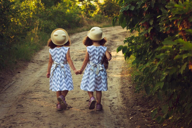 Glückliche Zwillingsschwesterkinder Mädchenschwester in einem Park, gehend auf die Straße, Händchenhalten Sonnenlicht und Ansicht stockbilder Glückliche Zwillingsschwesterkinder Mädchenschwester in einem Park, gehend auf die Straße, Händchenhalten Sonnenlicht und Ansicht stockbilder