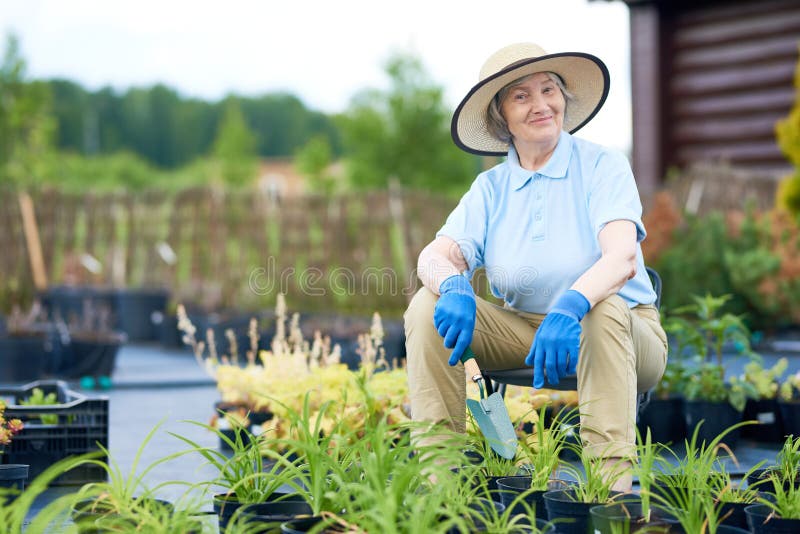 Glückliche ältere Frau, die im Garten aufwirft lizenzfreie stockbilder Glückliche ältere Frau, die im Garten aufwirft lizenzfreie stockbilder