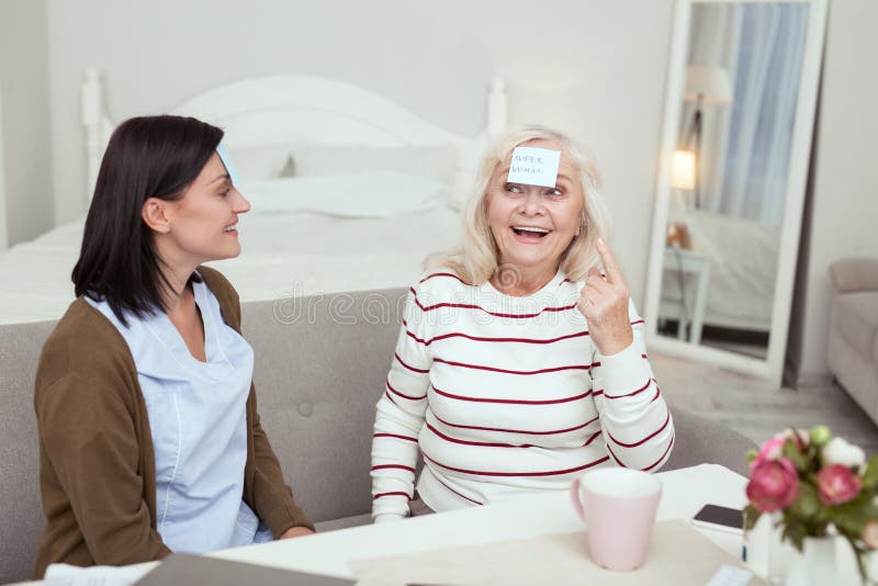Glückliche ältere Frau und Pflegekraft, die Spiel spielt stockfotos Glückliche ältere Frau und Pflegekraft, die Spiel spielt stockfotos