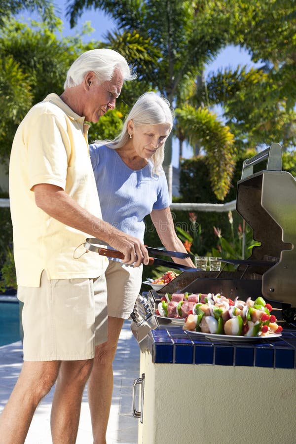 Glückliche ältere Paar-äußeres Kochen auf einem Grill stockfoto Glückliche ältere Paar-äußeres Kochen auf einem Grill stockfoto
