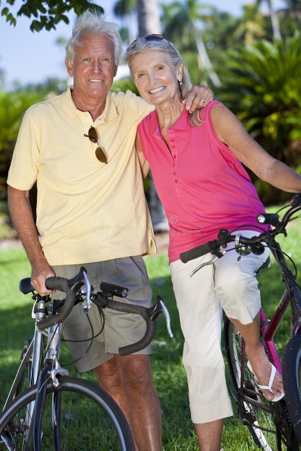 Happy senior men and women couple together cycling on bicycles in a park. Happy senior men and women couple together cycling on bicycles in a park