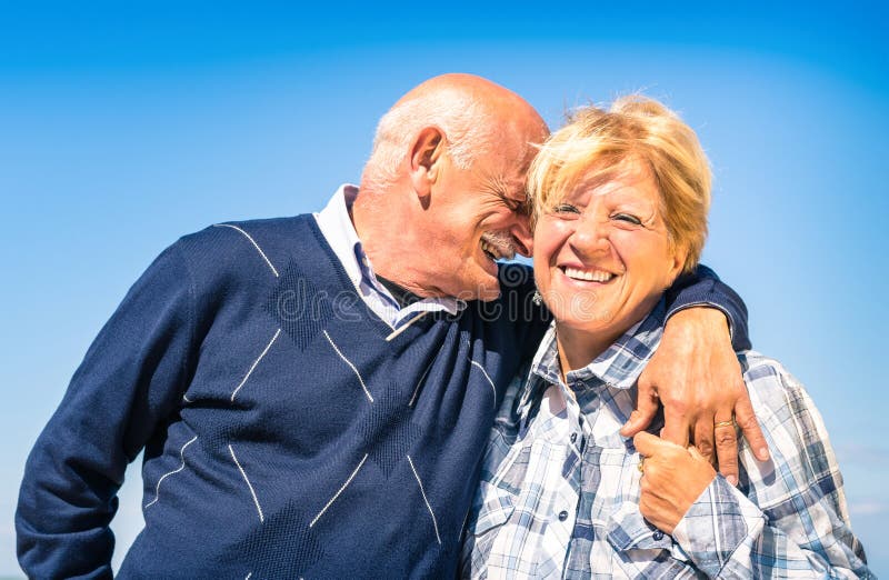 Happy senior couple in love during retirement - Joyful elderly lifestyle with men whispering and smiling with her wife. Happy senior couple in love during retirement - Joyful elderly lifestyle with men whispering and smiling with her wife