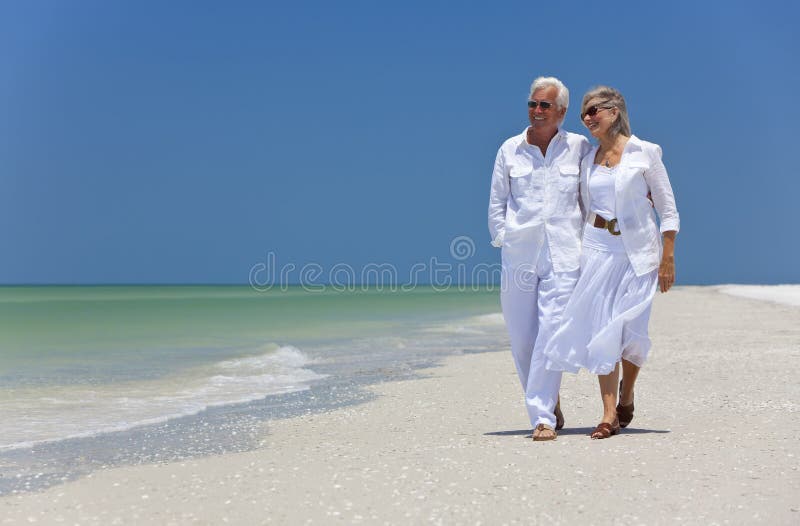 Glückliche ältere Paare, die auf einen tropischen Strand gehen