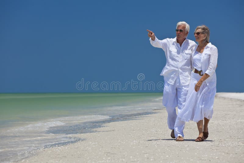 Glückliche ältere Paare, die auf Meer auf Strand zeigen