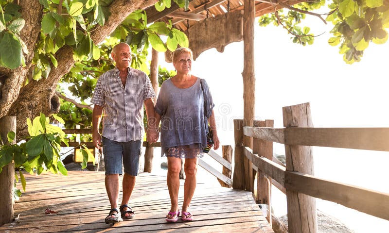 Glückliche ältere Paare, die Hand an der Koh Phangan-Strandpromenade halten - aktive ältere Personen und Reiselebensstilkonzept g