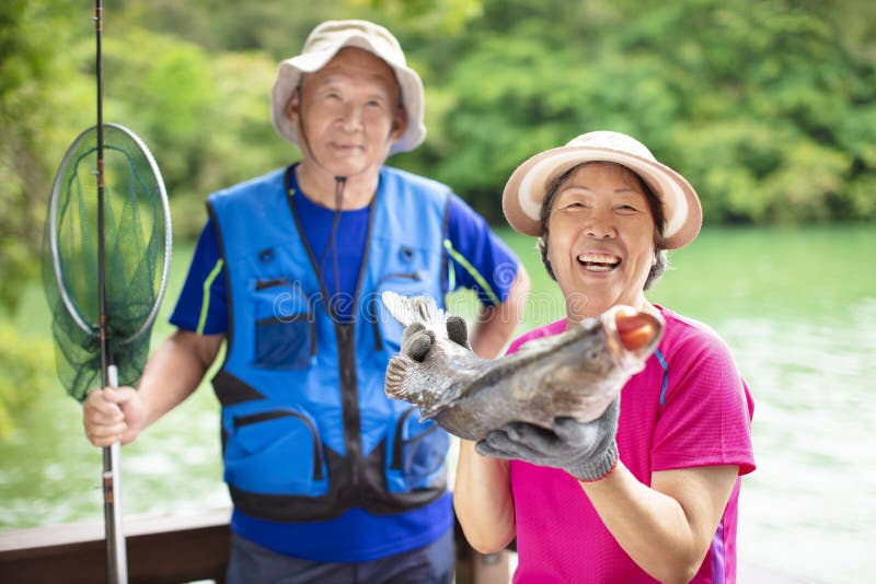 Glückliche ältere Paare, die am Seeufer fischen stockfotos Glückliche ältere Paare, die am Seeufer fischen stockfotos