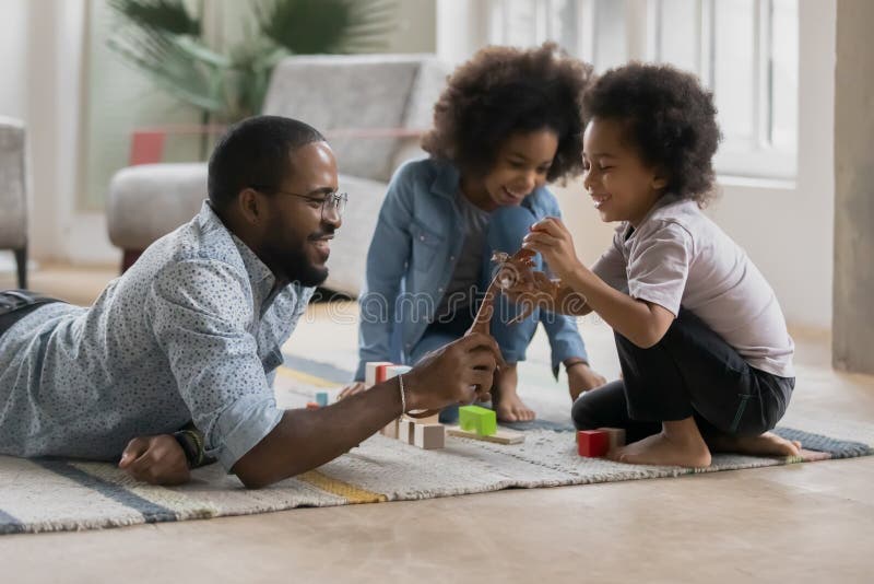 Glücklicher afroer-amerikanisch Vati und nette Kinder, die mit Spielzeug spielen lizenzfreies stockfoto