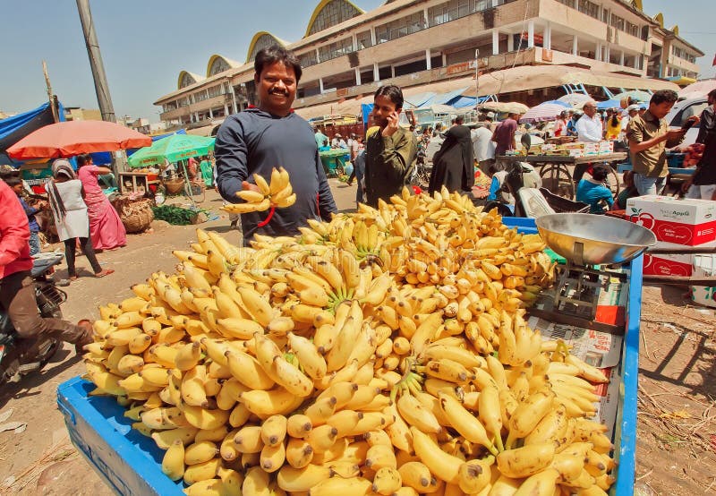 Glücklicher Bananenhändler, der Früchte auf gedrängtem Landwirtmarkt verkauft stockbild Glücklicher Bananenhändler, der Früchte auf gedrängtem Landwirtmarkt verkauft stockbild