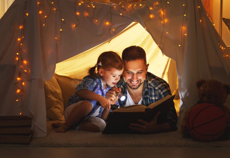 Glücklicher Familienvater und Kindertochter, die ein Buch im Zelt liest