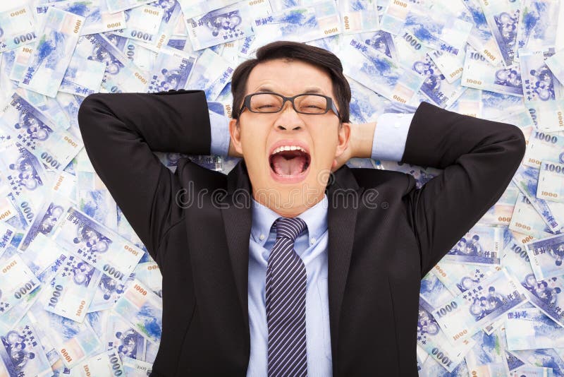 Glücklicher Geschäftsmann, der auf den Stapeln des neuen Taiwan-Dollars liegt lizenzfreie stockbilder Glücklicher Geschäftsmann, der auf den Stapeln des neuen Taiwan-Dollars liegt lizenzfreie stockbilder