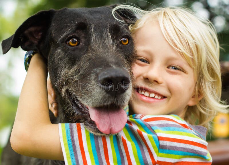 Glücklicher Junge, der liebevoll seinen Schoßhund umarmt