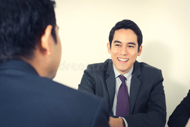 Glücklicher junger asiatischer Geschäftsmann in der Sitzung lizenzfreies stockbild Glücklicher junger asiatischer Geschäftsmann in der Sitzung lizenzfreies stockbild