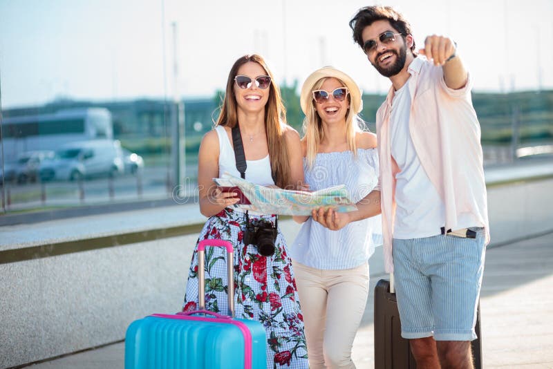 Glücklicher junger Mann, der zwei weiblichen Touristen Richtungen, stehend vor einem Flughafenabfertigungsgebäudegebäude gibt lizenzfreie stockfotografie Glücklicher junger Mann, der zwei weiblichen Touristen Richtungen, stehend vor einem Flughafenabfertigungsgebäudegebäude gibt lizenzfreie stockfotografie