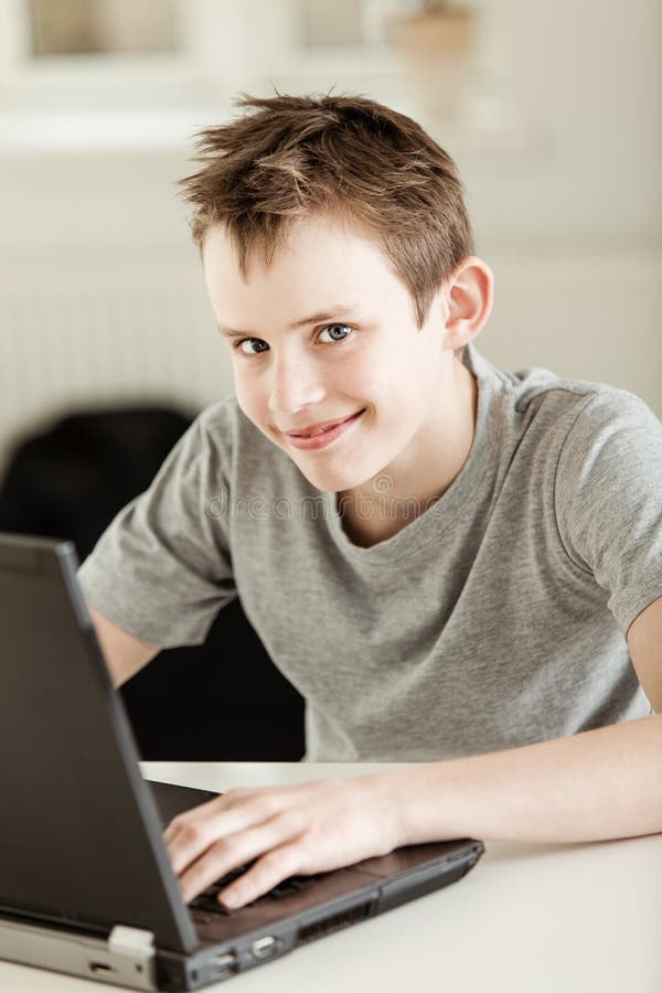 Glücklicher junger Schüler, der an einem Laptop arbeitet lizenzfreie stockfotos Glücklicher junger Schüler, der an einem Laptop arbeitet lizenzfreie stockfotos