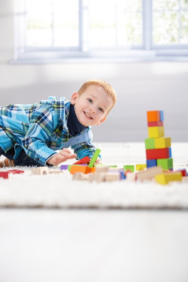 Glücklicher kleiner Junge, der mit Würfeln spielt lizenzfreies stockbild