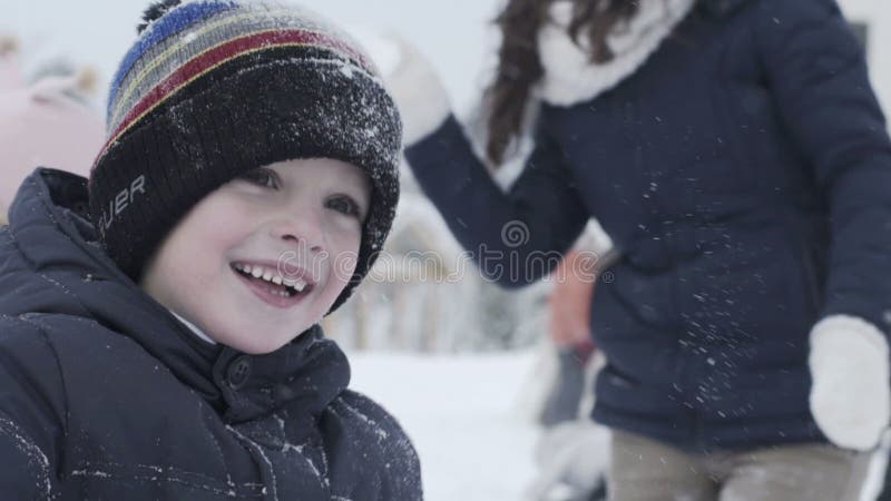 Glücklicher kleiner Junge und seine Familie, die mit Schnee spielt