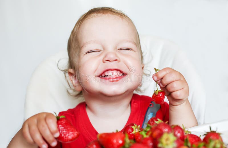 Glücklicher Kleinkindjunge, der Erdbeeren isst lizenzfreie stockfotografie Glücklicher Kleinkindjunge, der Erdbeeren isst lizenzfreie stockfotografie
