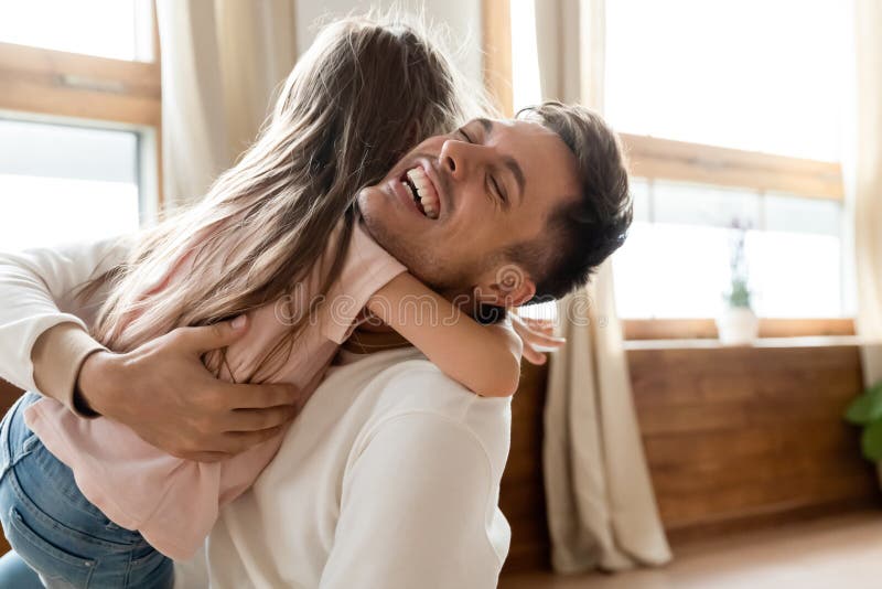 Glücklicher lachender Vater streichelt hübsche kleine Tochter. Papa streichelt wenig Tochter habe sie Wiedervereinigungsabschluß zu genießen. der Mädchenumarmung der hinteren Ansicht liebevoller Vater glaubende offene Gefühle der Hingabe der starken Verbindung der Liebe zum Ausdruck bringen. Frohe VaterschaftsVatertagskonzept