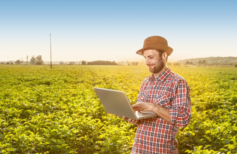 Glücklicher Landwirt mit Laptop-Computer vor Feld lizenzfreies stockfoto