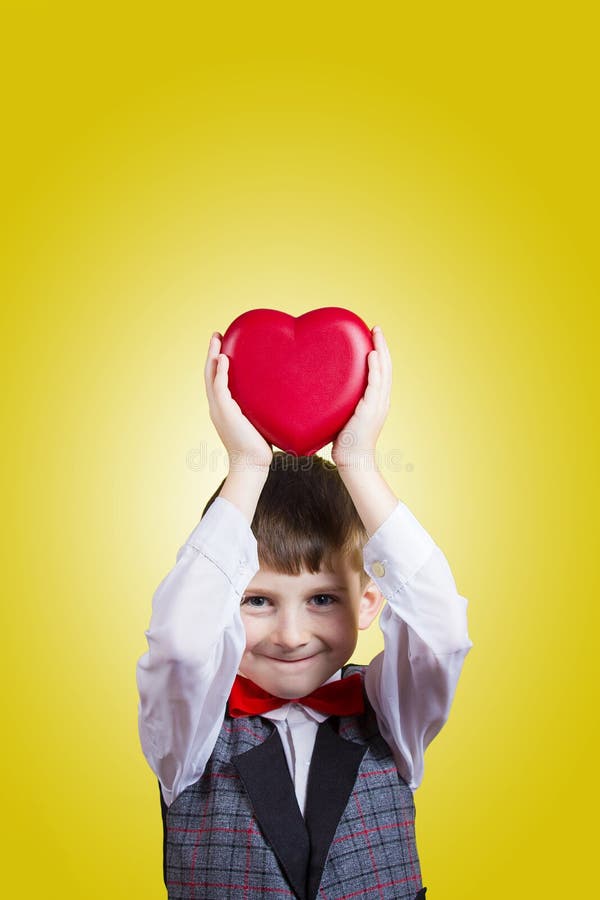 Glücklicher, lächelnder kleiner Junge, der rotes Herz hält lizenzfreie stockfotografie Glücklicher, lächelnder kleiner Junge, der rotes Herz hält lizenzfreie stockfotografie