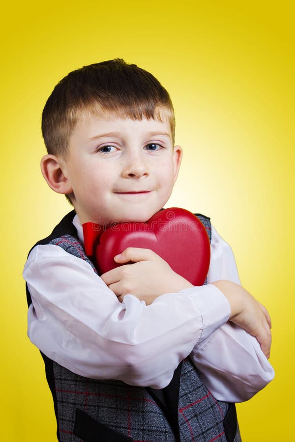 Glücklicher, lächelnder kleiner Junge, der rotes Herz hält lizenzfreies stockfoto Glücklicher, lächelnder kleiner Junge, der rotes Herz hält lizenzfreies stockfoto