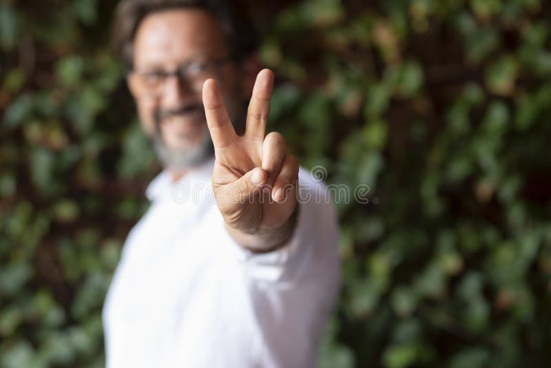 Glücklicher reifer Mann mit Brille und Siegeszeichen, während er gegen einen Kriecher steht, der das v-Zeichen zeigt. Portrait stockfotos