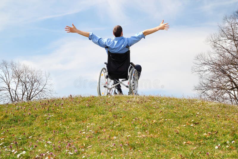 Glücklicher Rollstuhlfahrer auf einem grünen Hügel