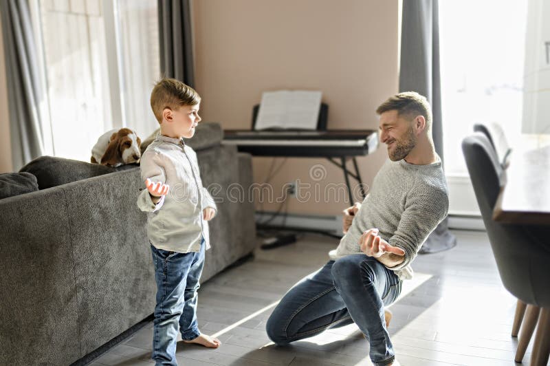 Glücklicher Vater und kleiner Sohn, der sich im Wohnzimmer amüsiert, spielen Gitarre lizenzfreie stockfotos
