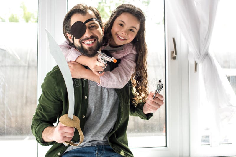 glücklicher Vater und Tochter, die an der Kamera beim zusammen spielen und Vortäuschen, Piraten zu sein lächelt stockfotografie glücklicher Vater und Tochter, die an der Kamera beim zusammen spielen und Vortäuschen, Piraten zu sein lächelt stockfotografie