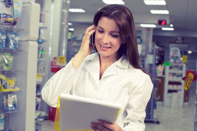 Glücklicher weiblicher Apotheker am Telefon in der Apotheke stockfotografie Glücklicher weiblicher Apotheker am Telefon in der Apotheke stockfotografie