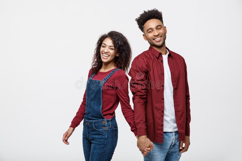 Glückliches Afroamerikanerpaarhändchenhalten und Schauen zurück lokalisiert auf Weiß lizenzfreie stockbilder Glückliches Afroamerikanerpaarhändchenhalten und Schauen zurück lokalisiert auf Weiß lizenzfreie stockbilder