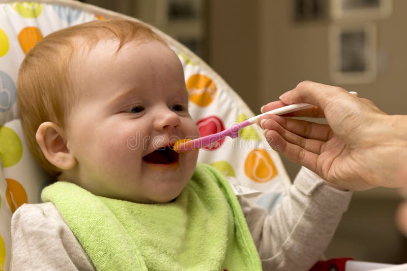 Glückliches Baby, das Brei isst stockbild