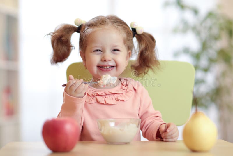Glückliches Baby, das Brei mit Löffel isst lizenzfreie stockbilder